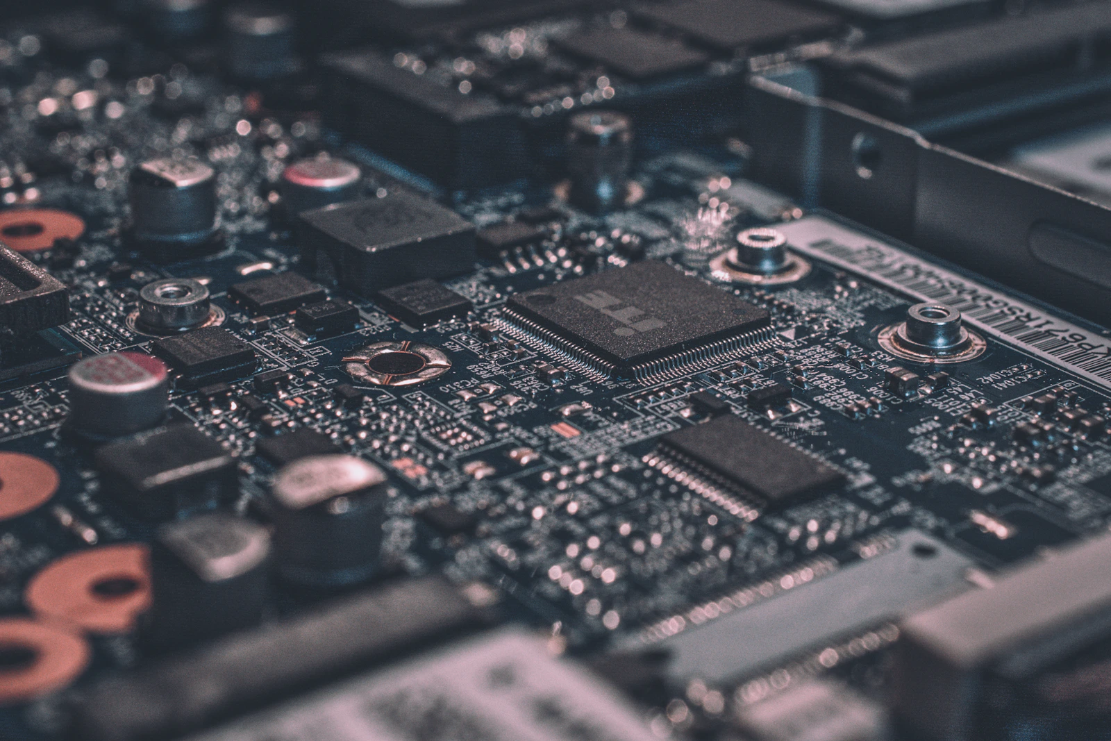 Placa de circuito eletrônico em tons escuros representando infraestrutura de tecnologia